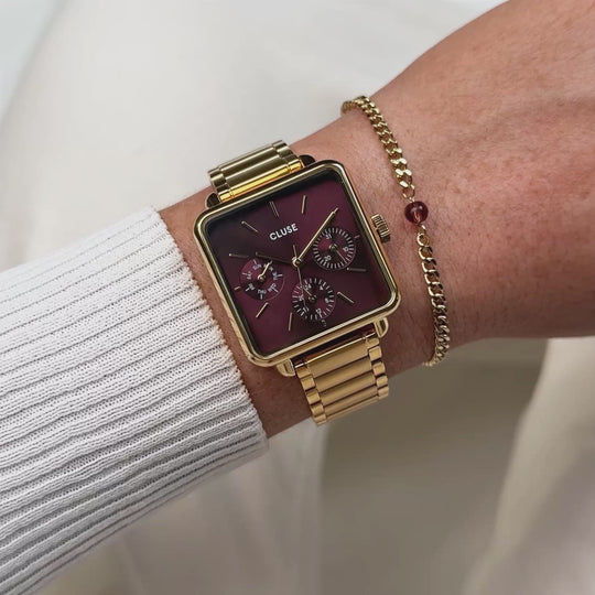 CLUSE Gift Box La Tétragone Multifunction Watch Steel, Dark Cherry & Bead Bracelet, Gold Colour CG13801 - moving wrist shot with watch and bracelet